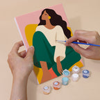 Hand holding a Color Block Ladies mini canvas while painting the details