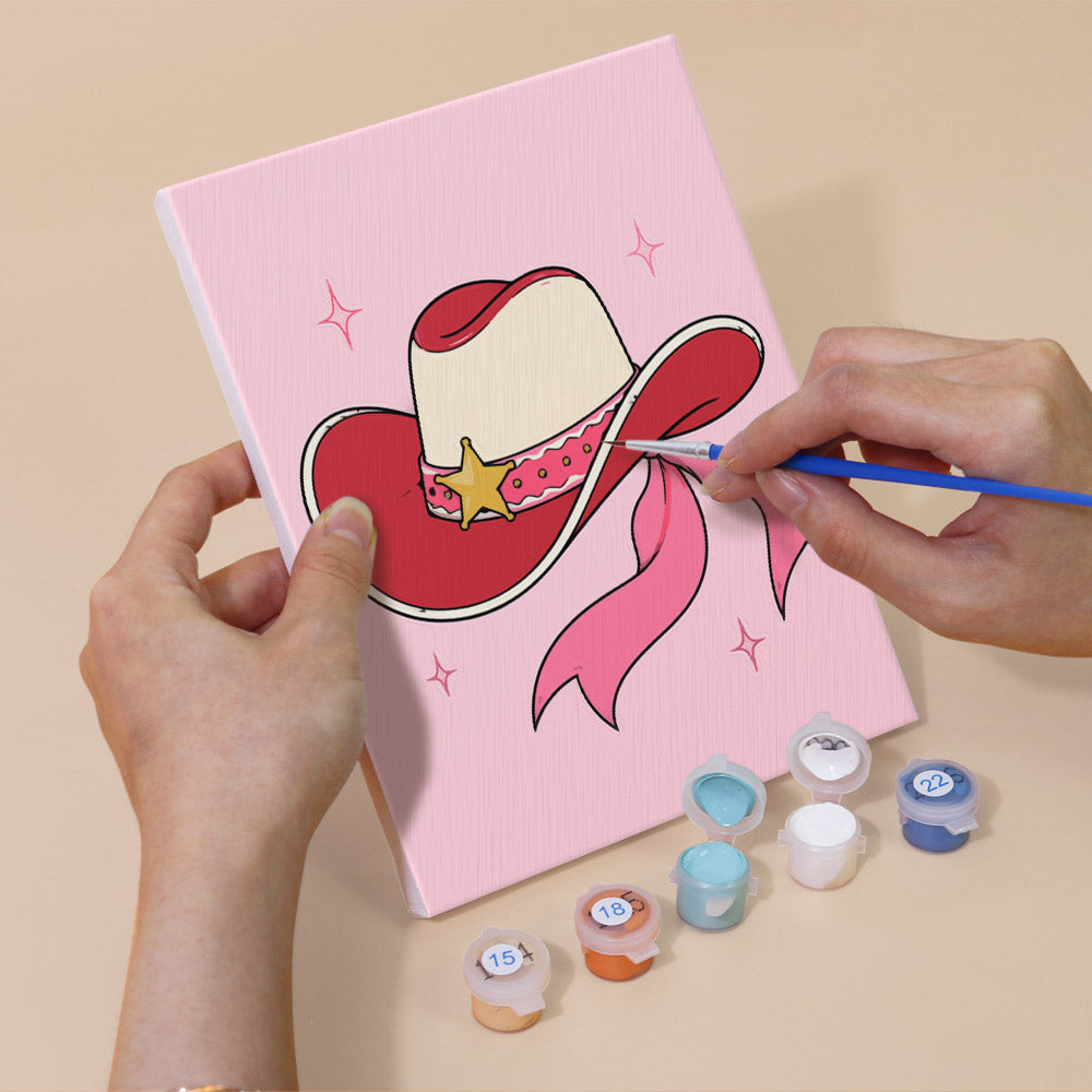 Finishing the pink cowgirl hat with ribbon on a mini paint by numbers canvas