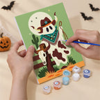 Hand holding a Cowboy Ghost Ranch mini canvas while painting the details
