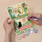 Hand holding a Cozy Cat Home mini canvas while painting the details