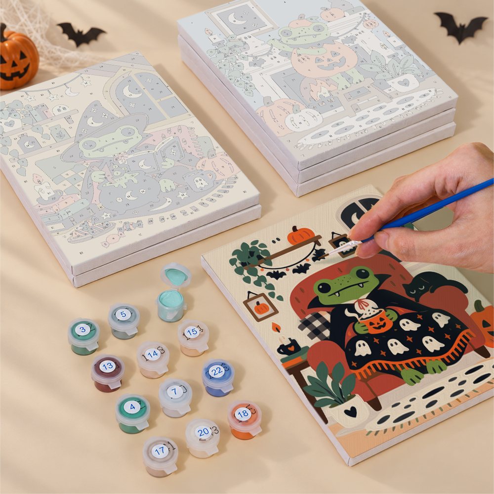 Painting one of the Cozy Frog Halloween designs next to a stack of mini canvases