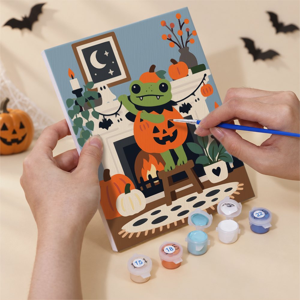 Hand holding a Cozy Frog Halloween mini canvas while painting the details