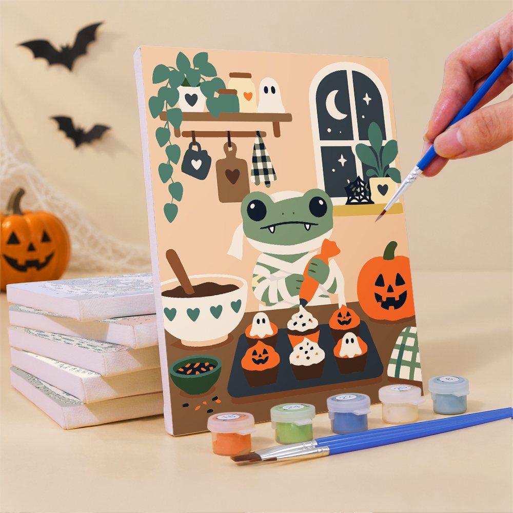 Painting a Cozy Frog Halloween mini canvas propped up beside numbered acrylic paints