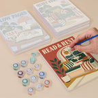 Painting one of the Cozy Reading Nook designs next to a stack of mini canvases