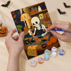Hand holding a Cozy Witch Cottage mini canvas while painting the details