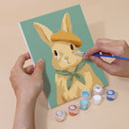 Hand holding a Dapper Bunnies mini canvas while painting the details
