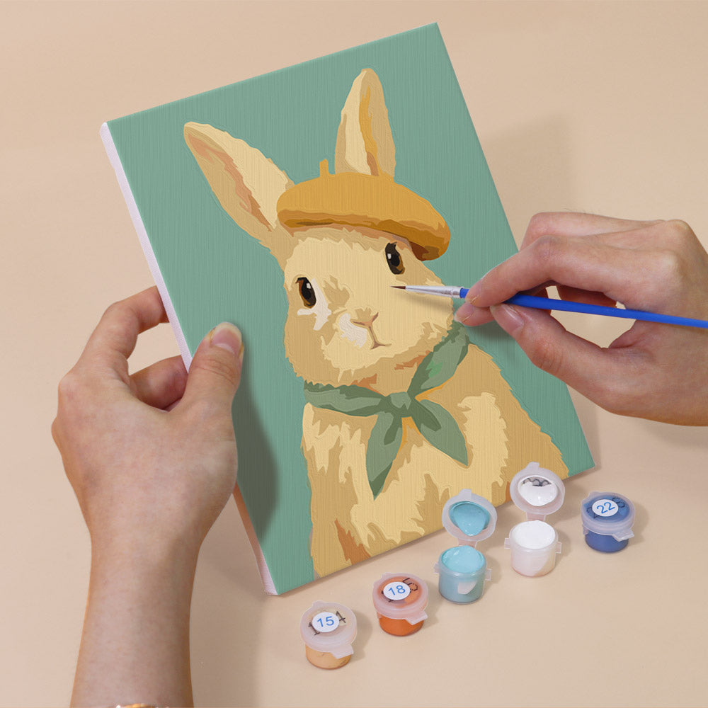 Hand holding a Dapper Bunnies mini canvas while painting the details