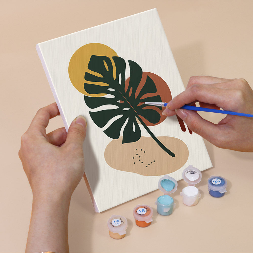 Hand holding an Earthy Leaves mini canvas while painting the details