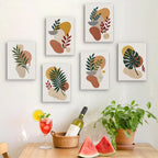 Six finished Earthy Leaves mini paintings hung on a wall above a table