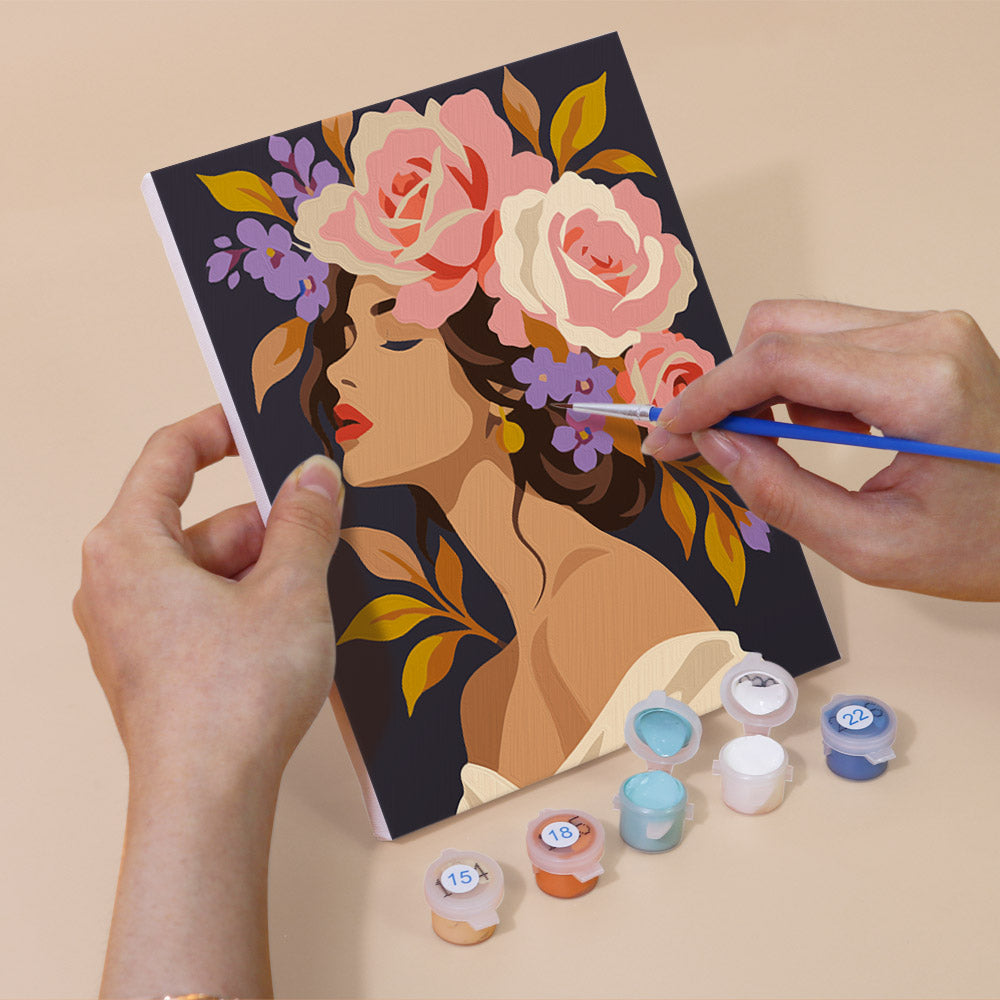 Hand holding a Flower Crowned Beauties mini canvas while painting the details