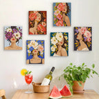 Six finished Flower Crowned Beauties mini paintings hung on a wall above a table