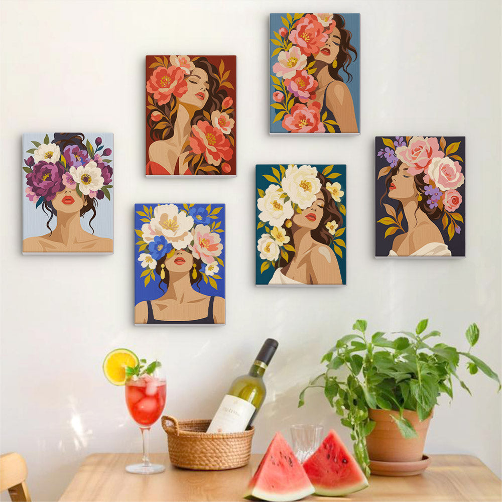 Six finished Flower Crowned Beauties mini paintings hung on a wall above a table