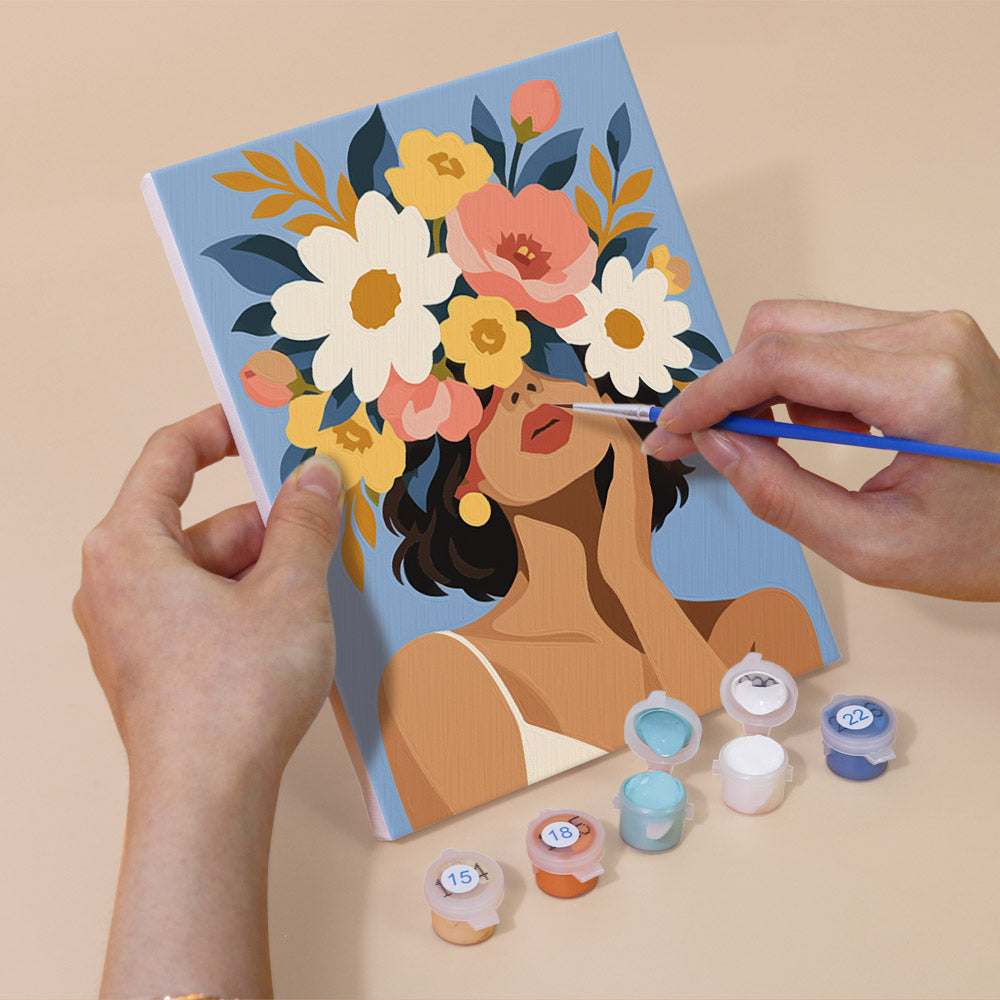 Hand holding a Flower Crowned mini canvas while painting the details