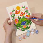 Hand holding a Folk Blossoms mini canvas while painting the details