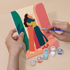 Hand holding a Friendship Hugs mini canvas while painting the details