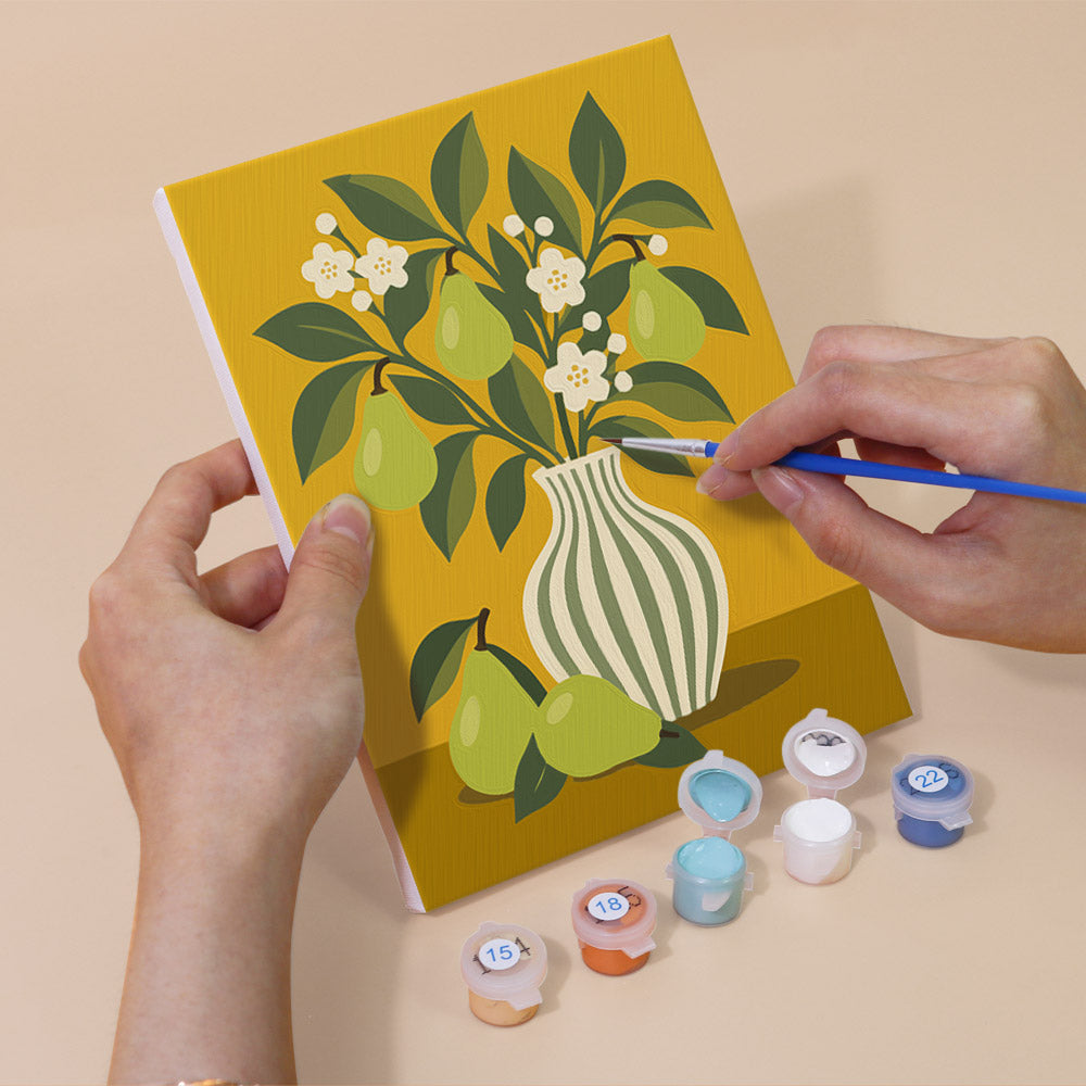Hand holding a Fruit & Flower Jugs mini canvas while painting the details
