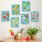 Six finished Fruit Splash mini paintings hung on a wall above a table