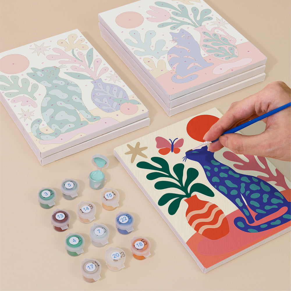 Painting one of the Garden Cats designs next to a stack of mini canvases