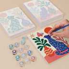 Painting one of the Garden Cats designs next to a stack of mini canvases