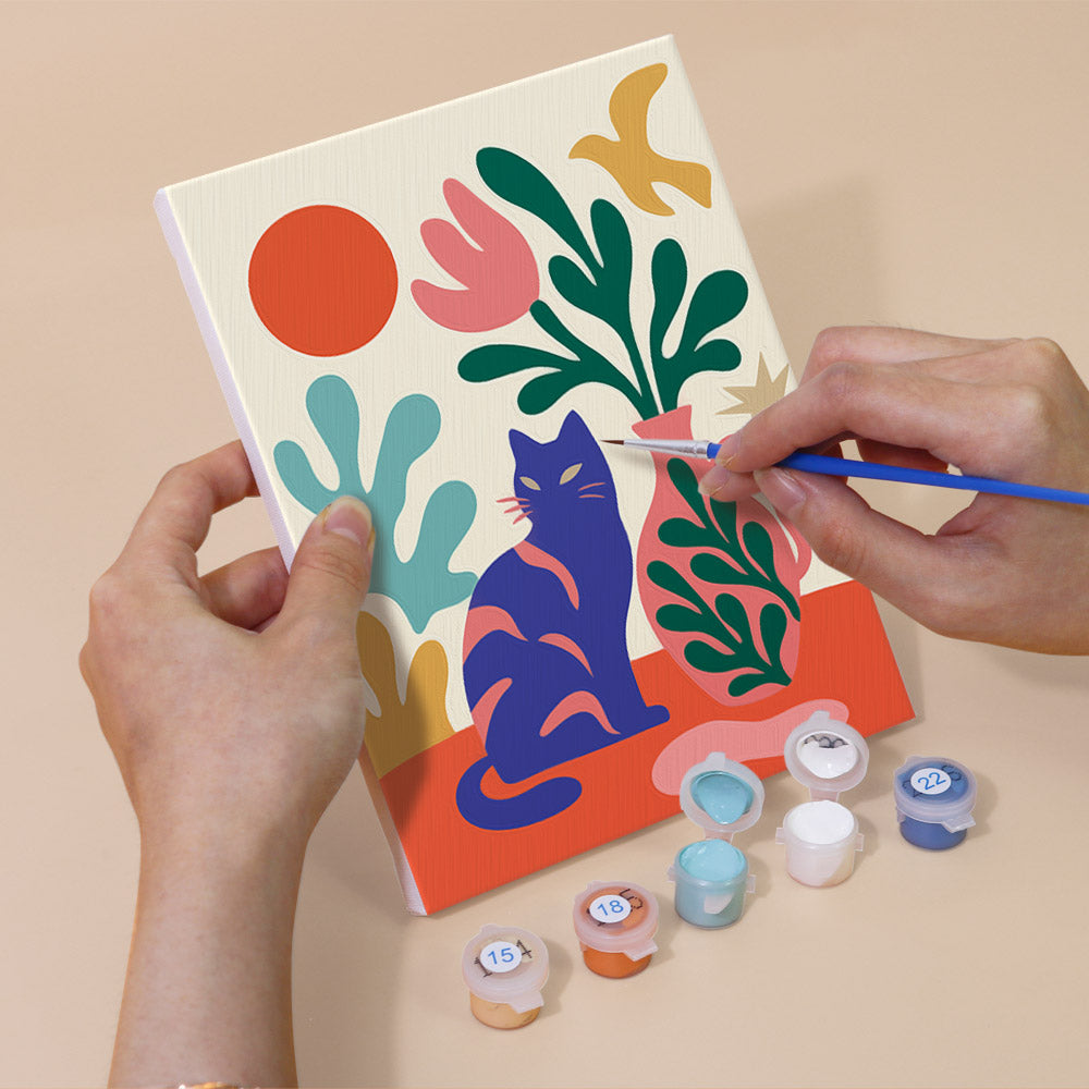 Hand holding a Garden Cats mini canvas while painting the details