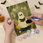 Hand holding a Garden Ghosts mini canvas while painting the details