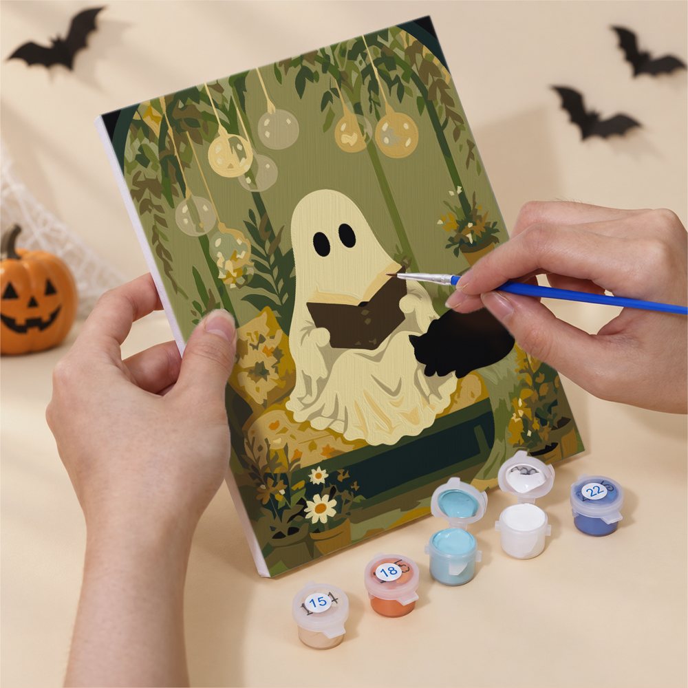 Hand holding a Garden Ghosts mini canvas while painting the details