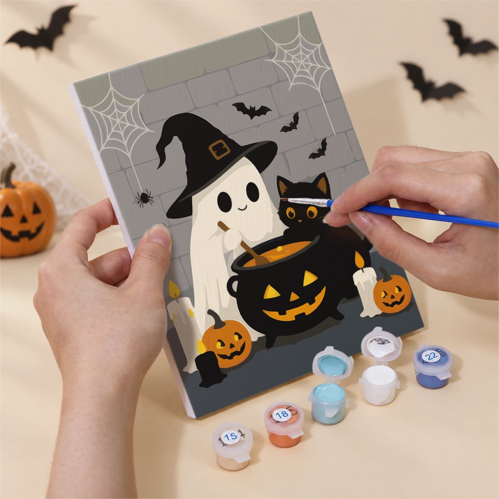 Hand holding a Ghostly Cauldrons mini canvas while painting the details