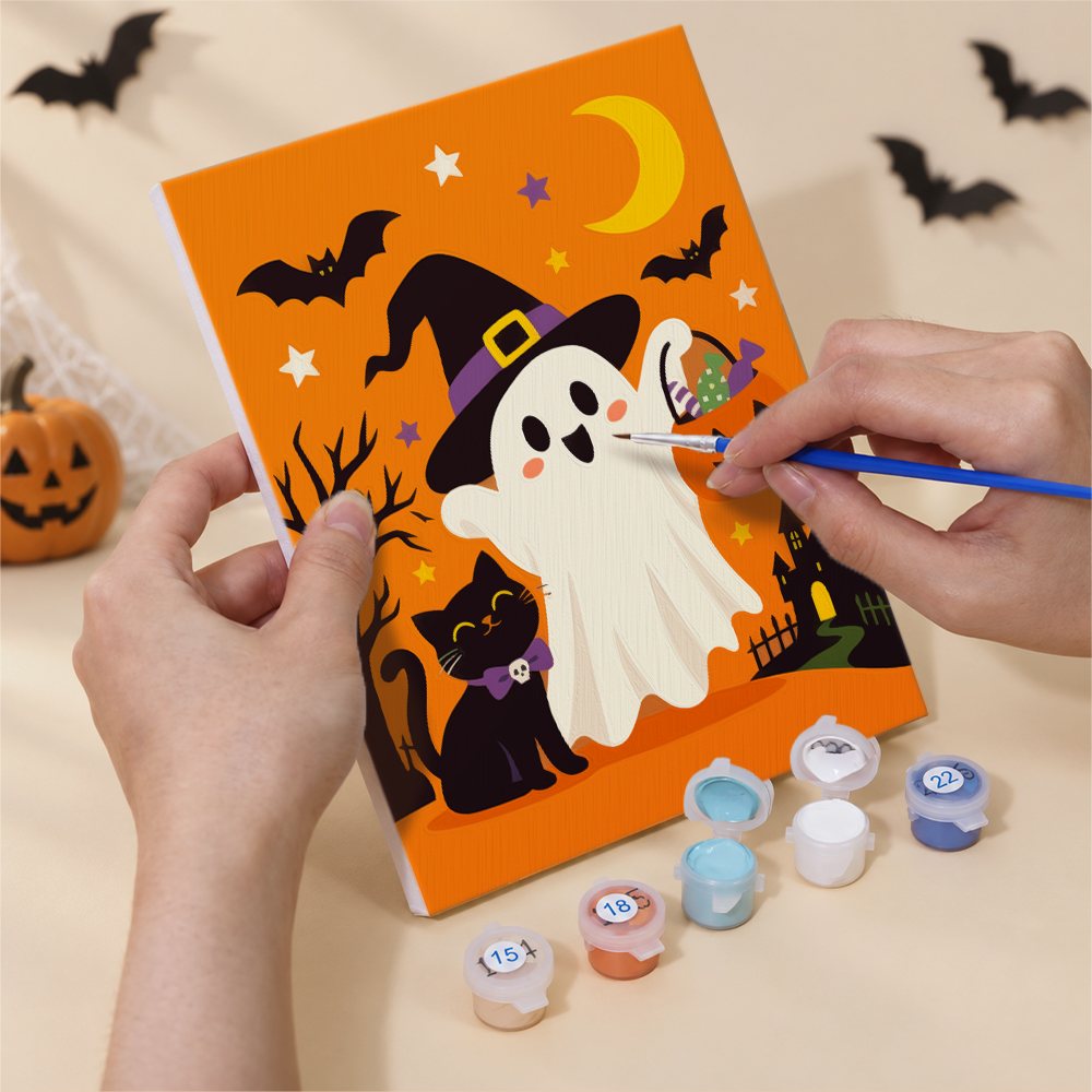 Hand holding a Ghosts in Witch Hats mini canvas while painting the details