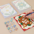 Painting one of the Good Mood Club designs next to a stack of mini canvases