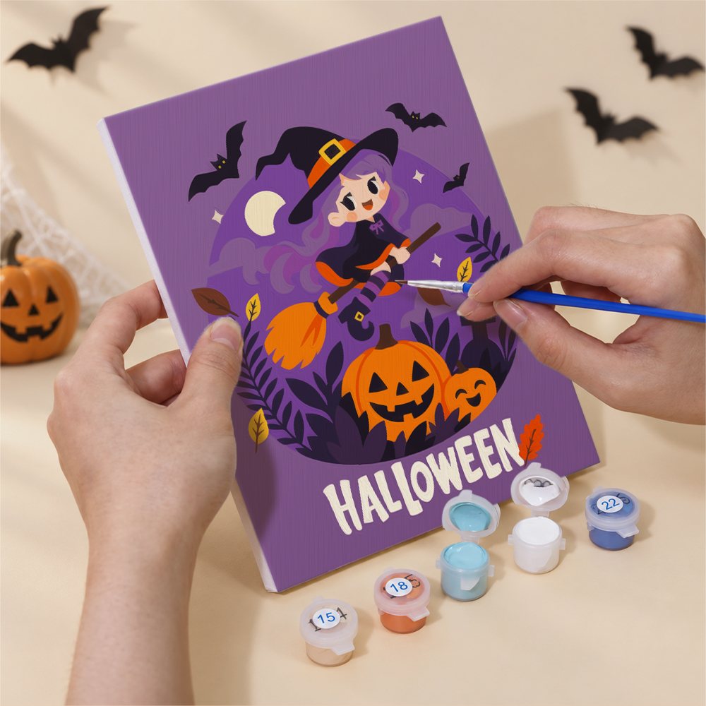 Hand holding a Halloween Banner Friends mini canvas while painting the details