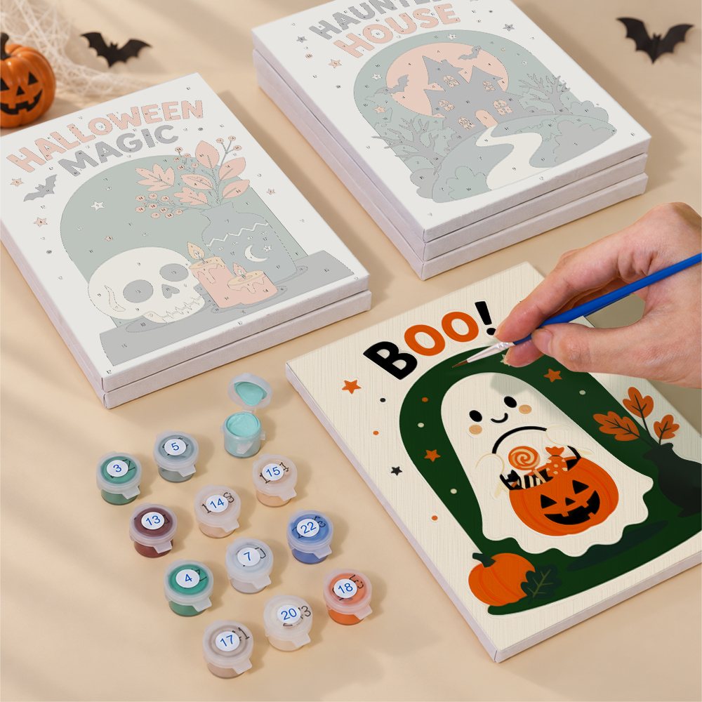 Painting one of the Halloween Greetings designs next to a stack of mini canvases