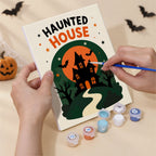 Hand holding a Halloween Greetings mini canvas while painting the details