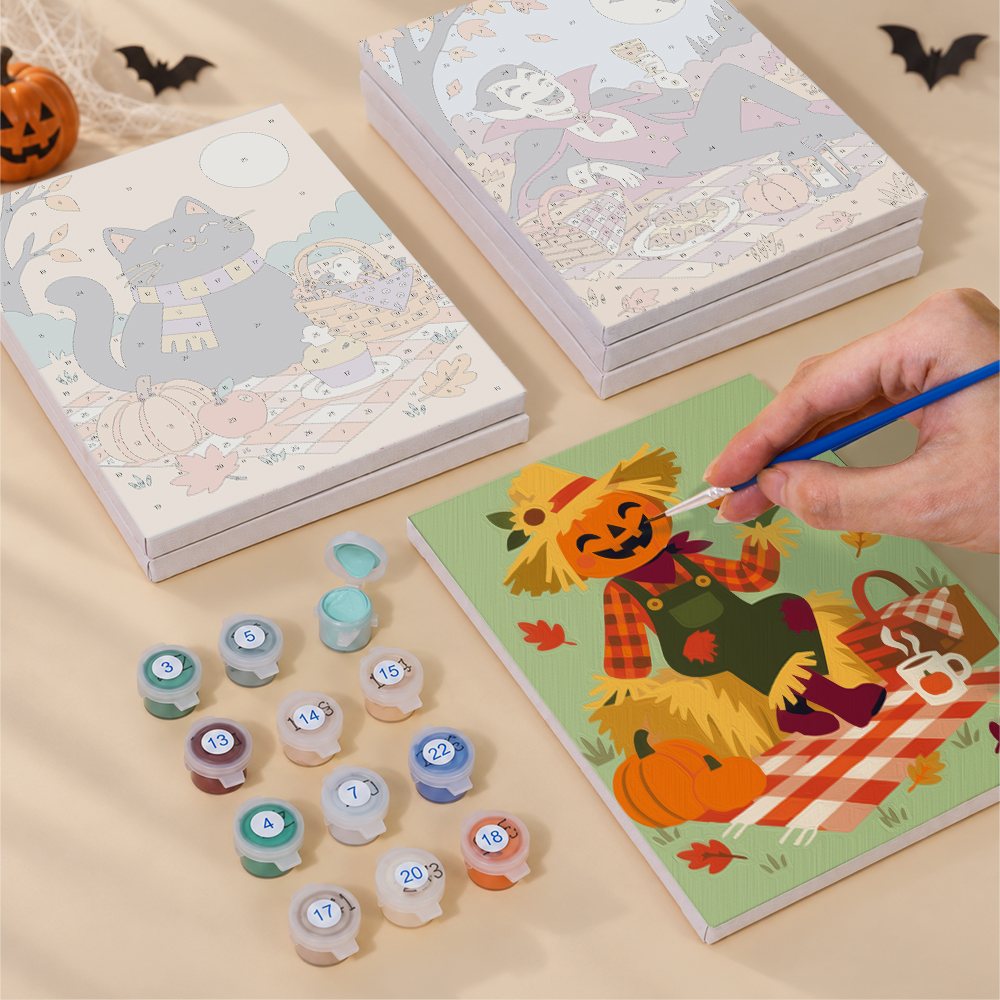 Painting one of the Halloween Picnic Party designs next to a stack of mini canvases