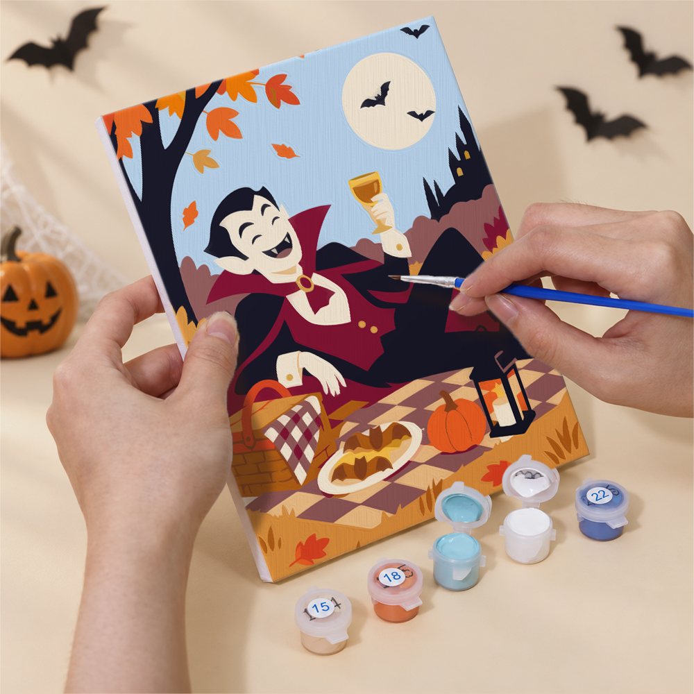 Hand holding a Halloween Picnic Party mini canvas while painting the details