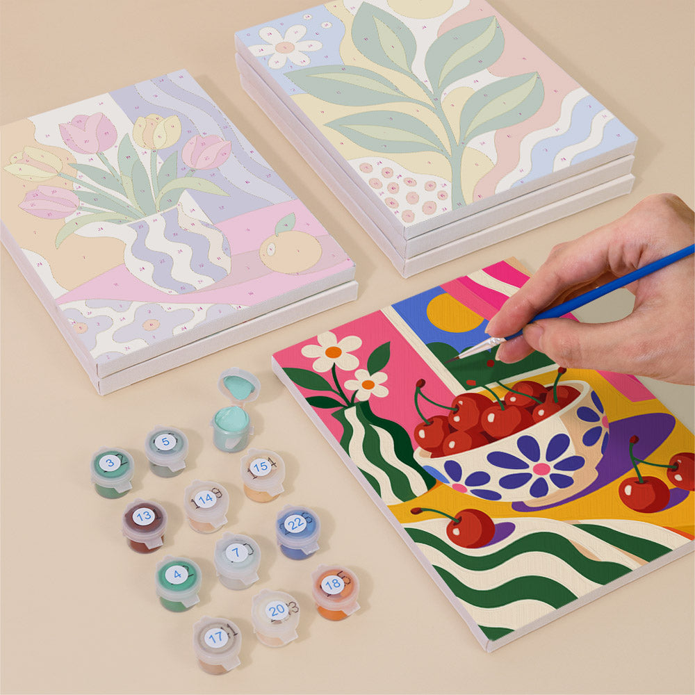 Painting one of the Happy Hues designs next to a stack of mini canvases