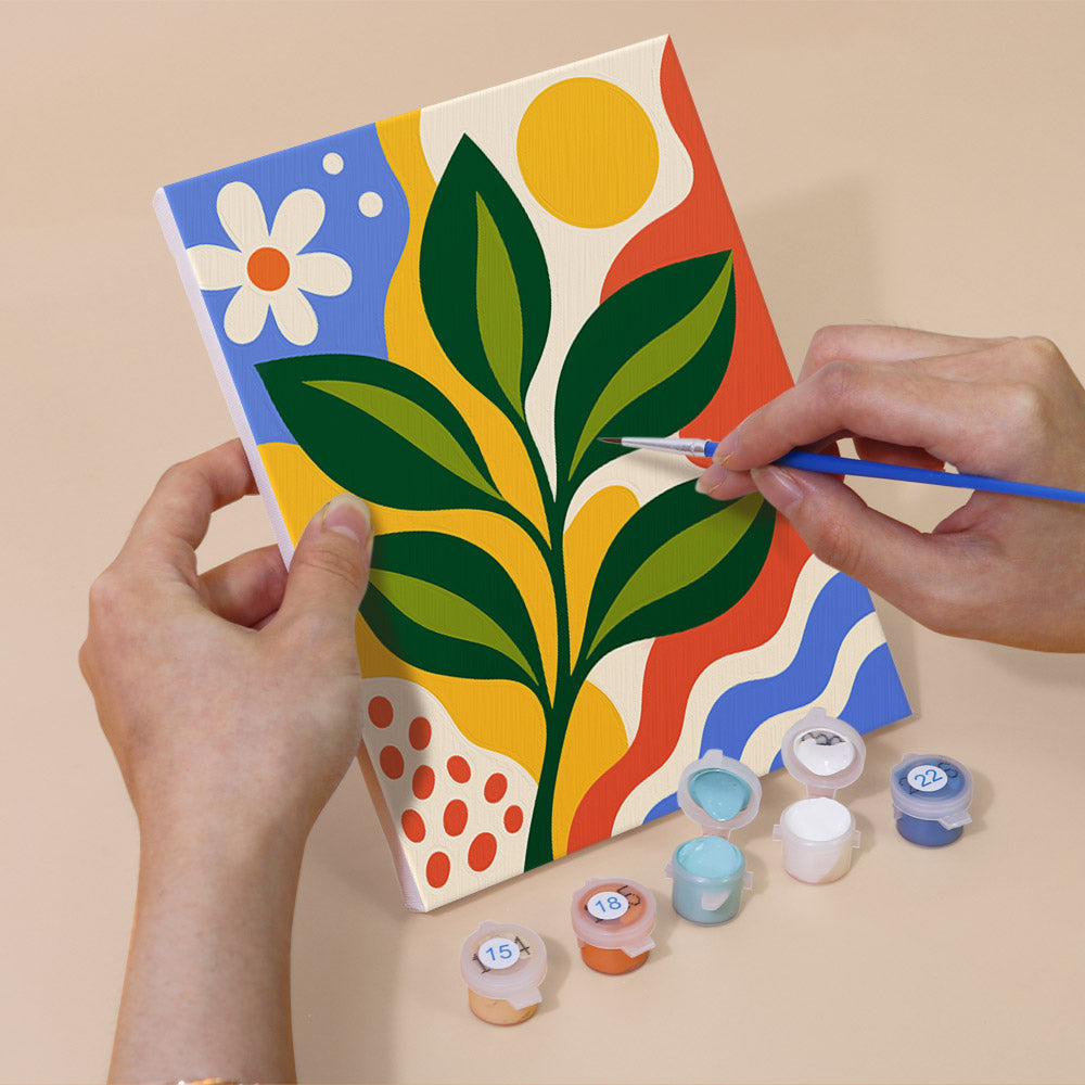 Hand holding a Happy Hues mini canvas while painting the details
