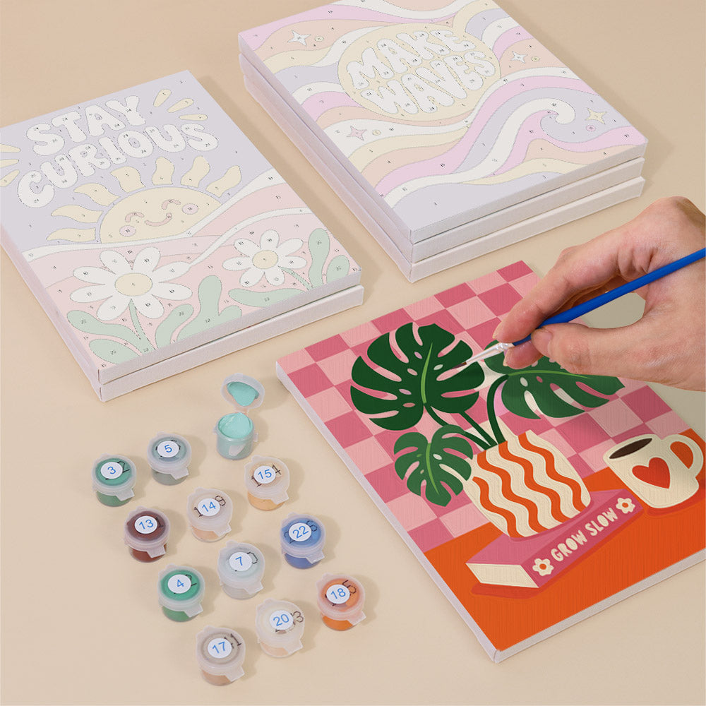 Painting one of the Happy Words designs next to a stack of mini canvases