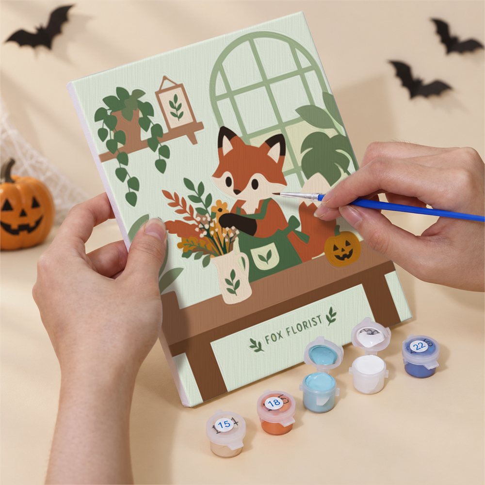 Hand holding a Harvest Garden Friends mini canvas while painting the details