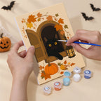 Hand holding a Harvest Hauntings mini canvas while painting the details