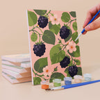 Painting a Harvest Patterns mini canvas propped up beside numbered acrylic paints