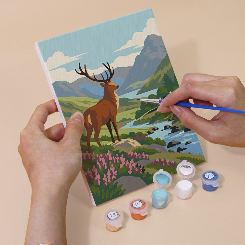 Hand holding a Highland Journey mini canvas while painting the details