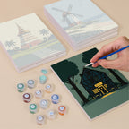 Painting one of the Homes Around the World designs next to a stack of mini canvases