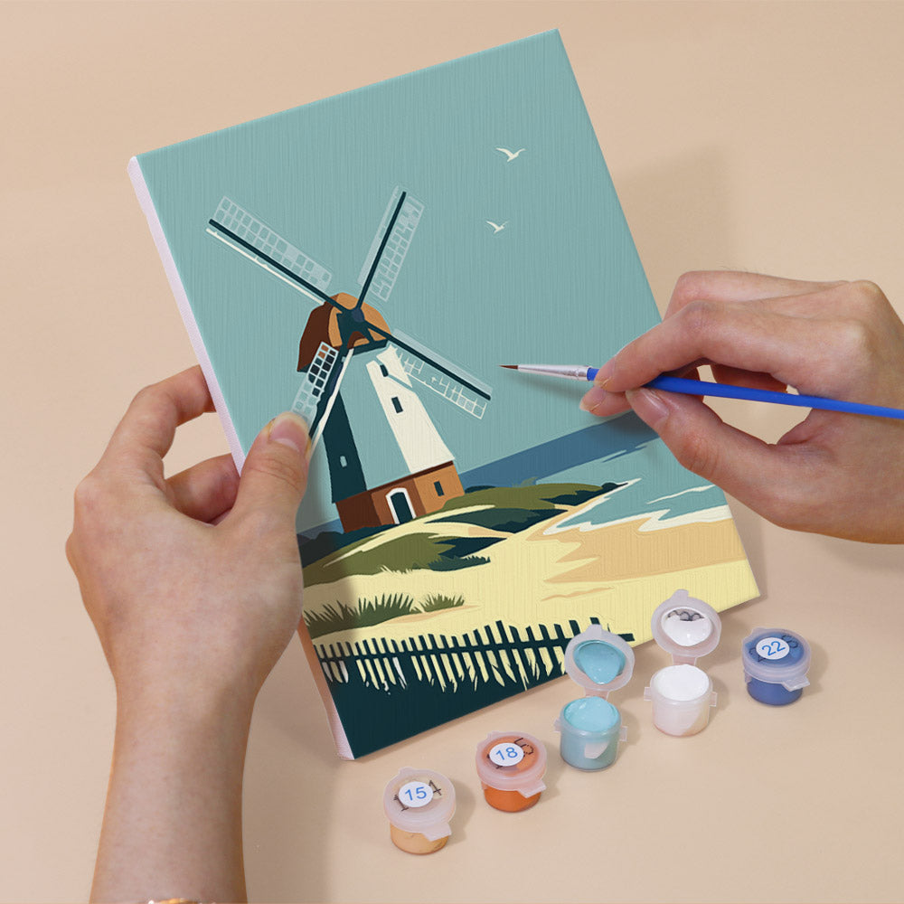 Hand holding a Homes Around the World mini canvas while painting the details