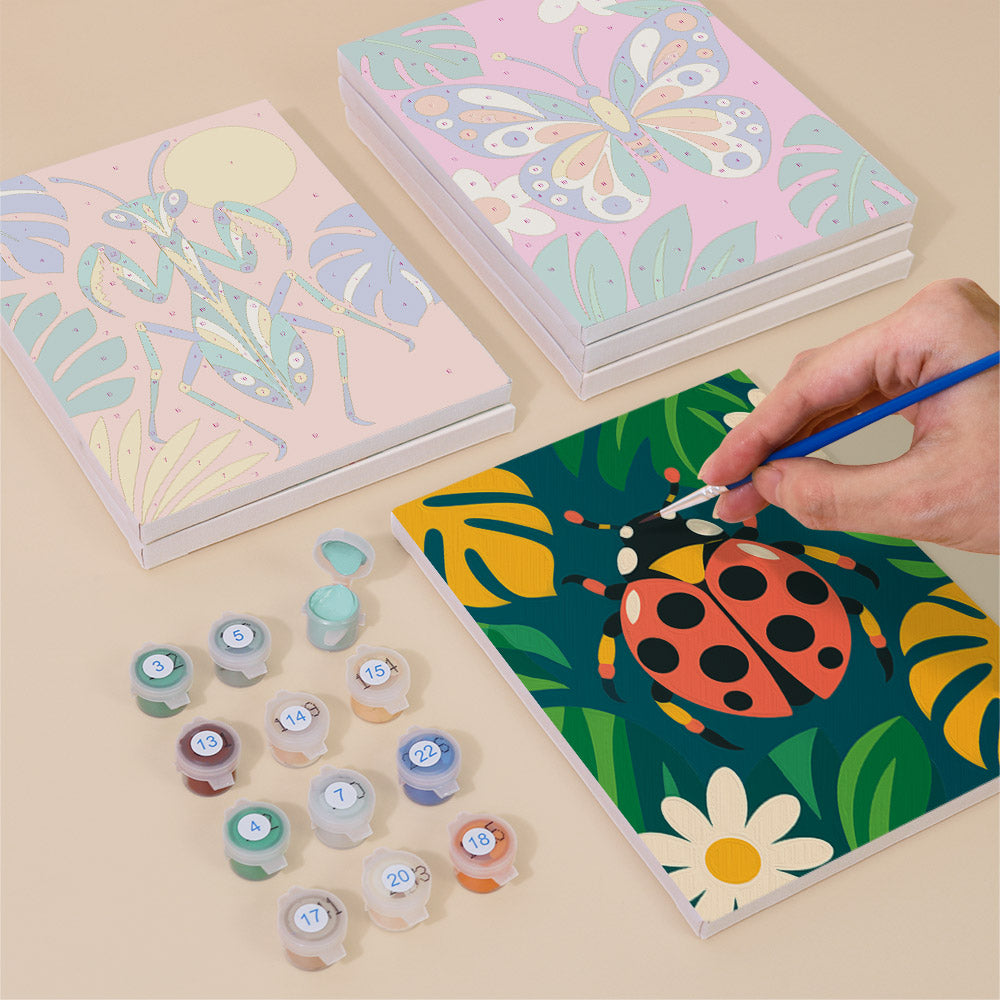 Painting one of the Jungle Bugs designs next to a stack of mini canvases