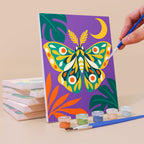 Painting a Jungle Bugs mini canvas propped up beside numbered acrylic paints