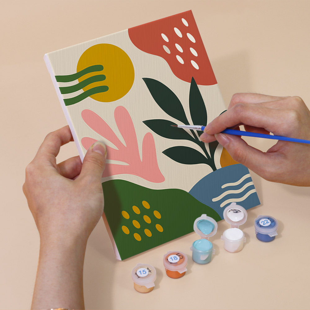 Hand holding a Jungle Collage mini canvas while painting the details