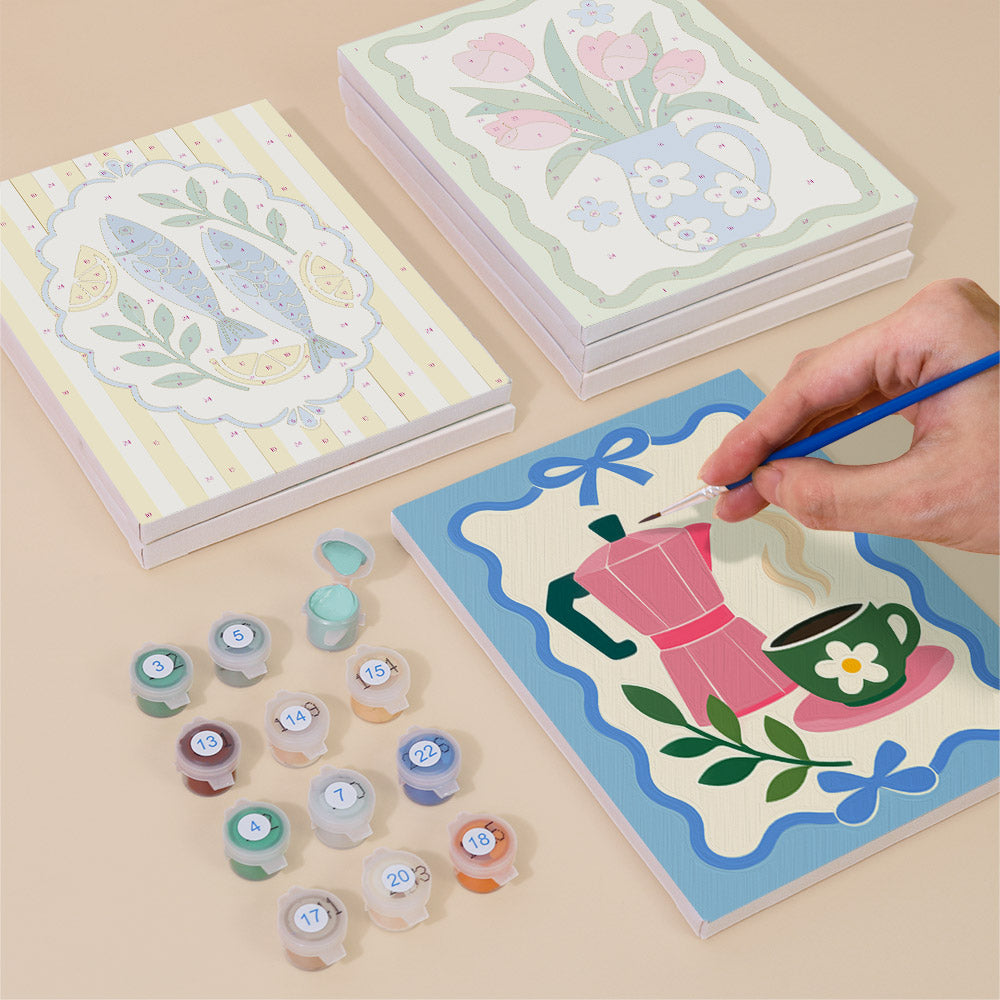 Painting one of the Kitchen Charm designs next to a stack of mini canvases