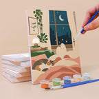 Painting a Lazy Sundays mini canvas propped up beside numbered acrylic paints