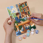 Hand holding a Library Hours mini canvas while painting the details