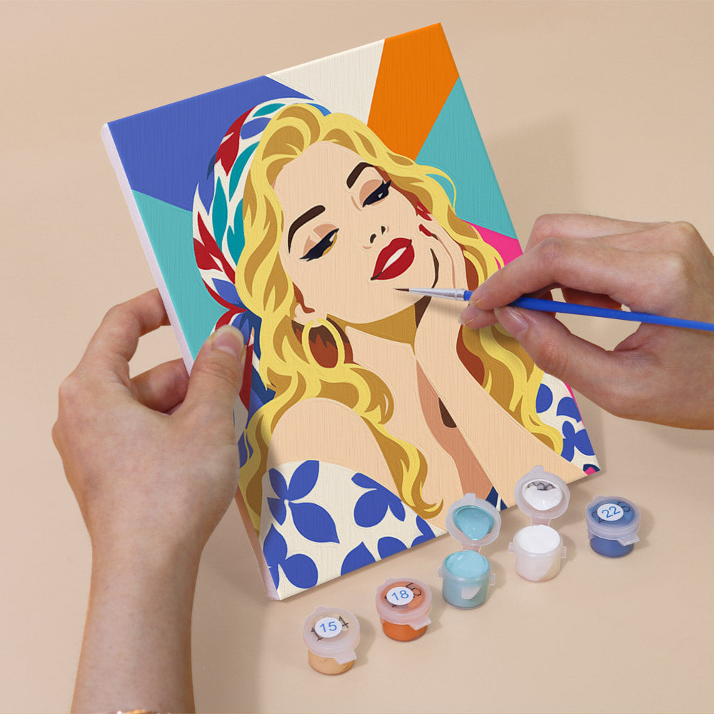 Hand holding a Lipstick & Attitude mini canvas while painting the details